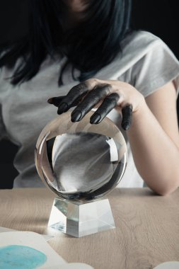 Elinde siyah boyayla falcı görüntüsü vardı. Elinde kristal küre vardı. Sulu boya tablosu, siyah masanın üzerindeydi.