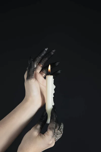 Обрезанный Вид Черных Раскрашенных Рук Ведьмы Держащих Горящую Свечу Изолированной — стоковое фото