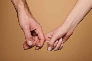 cropped view of man and woman holding fingers isolated on beige clipart