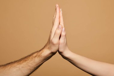 cropped view of man and woman giving high five isolated on beige clipart