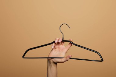 Boş askıyı tutan kadının bej renkte izole edilmiş görüntüsü