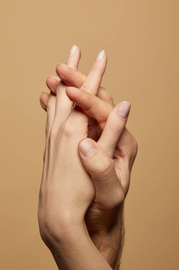 partial view of man and woman holding hands isolated on beige clipart