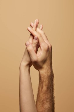 Bej üzerinde el ele tutuşan kadın ve erkeğin kısmi görüntüsü
