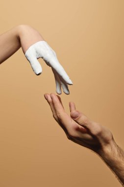 cropped view of man and woman with painted hand touching each other isolated on beige clipart