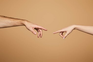 Kırpılmış bej rengi parmaklarla birbirine ulaşan erkek ve kadın manzarası