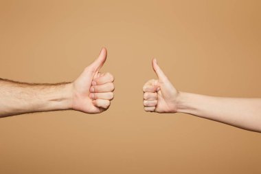 cropped view of man and woman showing thumbs up isolated on beige clipart