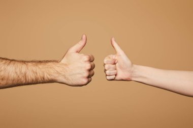 cropped view of man and woman showing thumbs up isolated on beige clipart