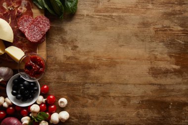 Top view of ingredients for pizza on wooden background