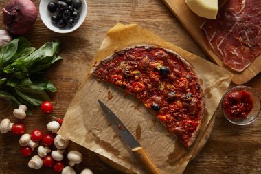 Top view of delicious pizza on parchment paper on wooden background
