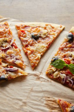 Lezzetli İtalyan pizzası, zeytinli, ahşap masadaki kağıt fırınında.