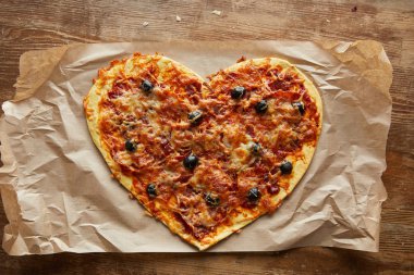 Lezzetli İtalyan pizzasının kalbi ahşap masada kağıt üzerinde.