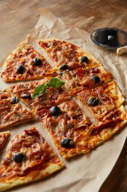 Kalbe sahip leziz İtalyan pizzasını yakın plan. Tahta masadaki pizza bıçağının yanında kağıt parçalarına ayırmışlar.