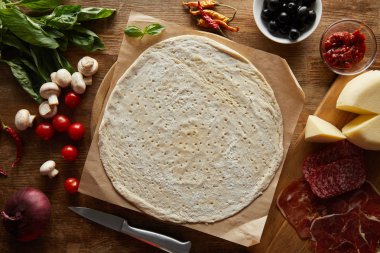 Tahta masada pizza malzemeleriyle çiğ hamur manzarası.