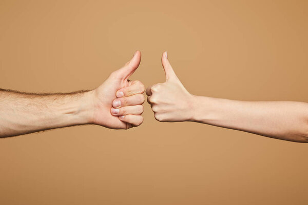 cropped view of man and woman showing thumbs up isolated on beige