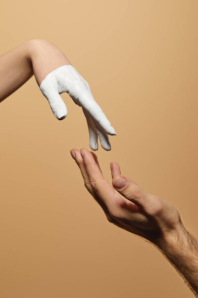 cropped view of man and woman with painted hand touching each other isolated on beige