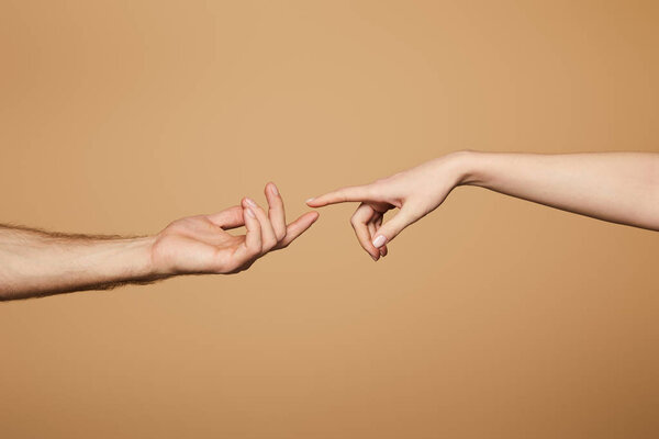 cropped view of man and woman reaching each other with fingers isolated on beige