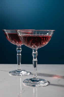 Beyaz mermer yüzeydeki kırmızı şarap kadehleri mavi üzerine izole edilmiş. 