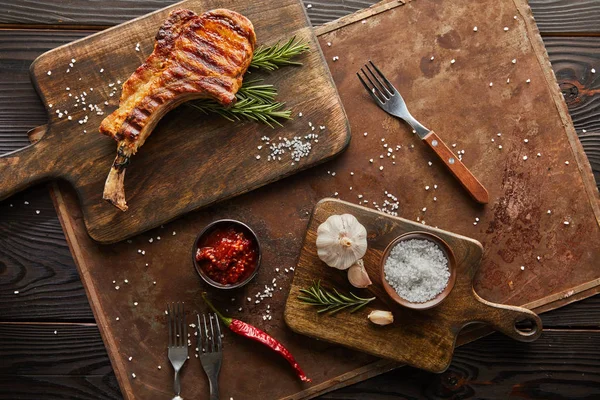 Top view of ribeye steak on cutting board with chili sauce and garlic on stone board on wooden background — Stock Image Top View Ribeye Steak Cutting Board Chili Sauce Garlic Stone Stock Picture