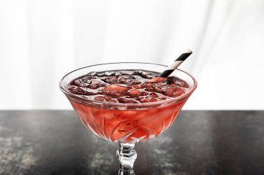 red cocktail with striped straw and ice cubes on white  clipart
