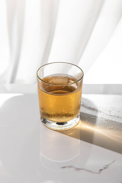 glass of whiskey on white marble surface 