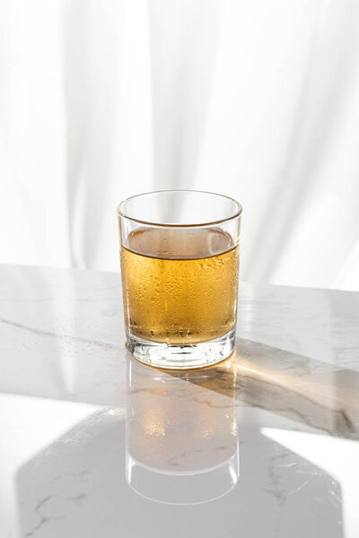 wet glass with strong whiskey on white with copy space 