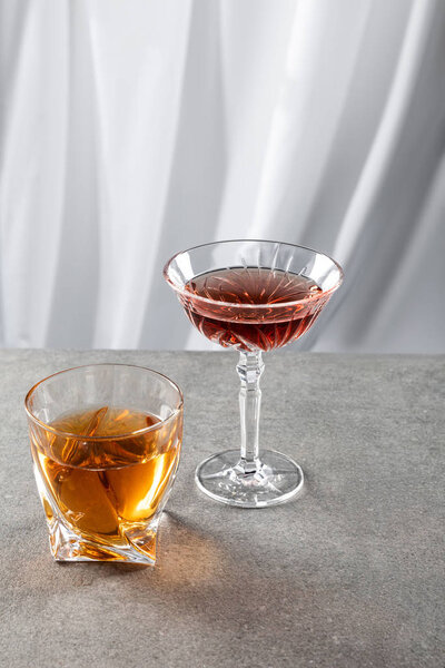 red wine near glass of strong cognac on white 