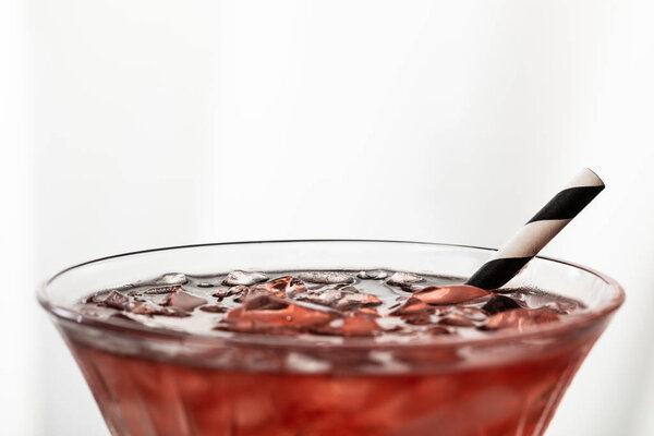 selective focus of cosmopolitan cocktail with striped straw and ice cubes on white 