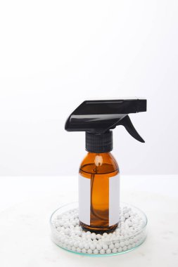 Laboratuvar bardağının içinde, dekoratif boncuklarla izole edilmiş kozmetik yağı şişesi.