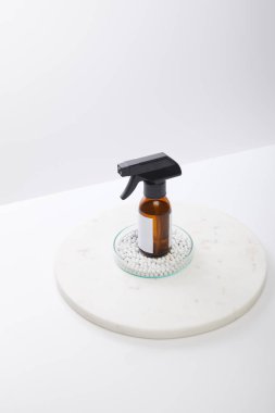 Yüksek açılı cam laboratuvar vitrininde kozmetik yağ şişesi ve gri renkli boncuklar var. 
