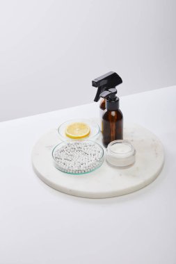 Yüksek açılı yağ şişeleri, kozmetik krem ve gri üzerinde limon ve boncuklar bulunan laboratuvar vitrinleri.