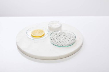 Dekoratif boncuklu laboratuvar vitrinleri, bir dilim limon ve kozmetik krem gri büfede izole edilmiş. 