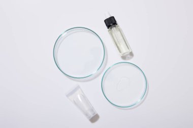 Top view of laboratory glassware, cosmetic tube and bottle of oil on grey background clipart