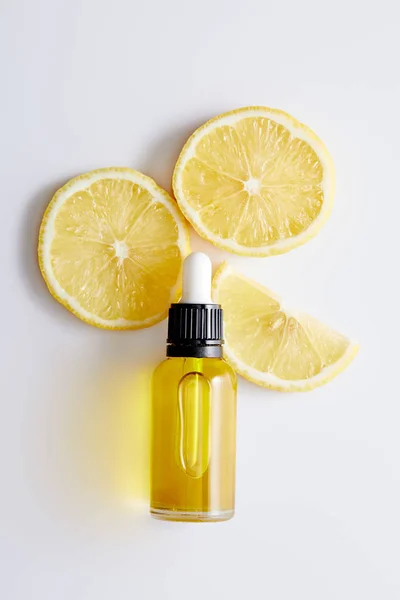 白い背景にレモンのスライスと化粧品油のボトルのトップビュー — ストック写真