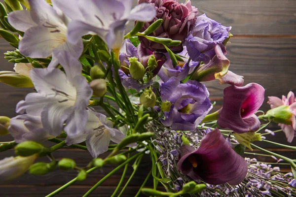 selective focus of violet and purple floral bouquet on wooden table