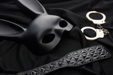 Siyah tekstil arka planında tavşan maskesi ve seks oyuncakları