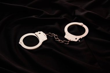 metal handcuffs on black textile background clipart