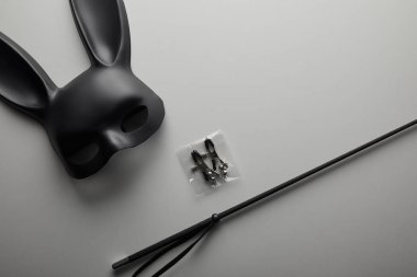 Beyaz arka planda siyah tavşan maskesi ve seks oyuncakları.