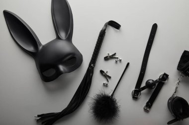 Beyaz arka planda siyah tavşan maskesi ve seks oyuncakları.