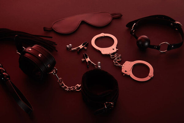 секс-игрушки при темном освещении на красном фоне
