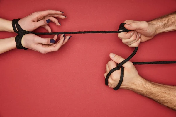 Visão Cortada Homem Segurando Corda Mãos Femininas Amarradas Isoladas Vermelho — Fotografia de Stock