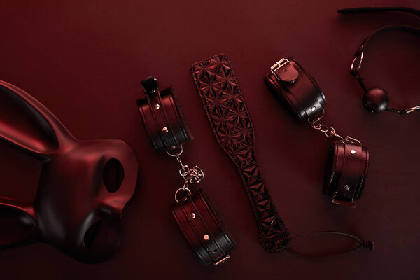 вид секс-игрушек при темном освещении на красном фоне
