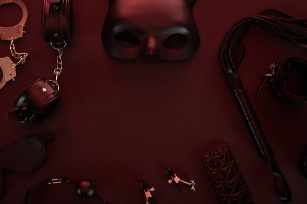 вид секс-игрушек при темном освещении на красном фоне
