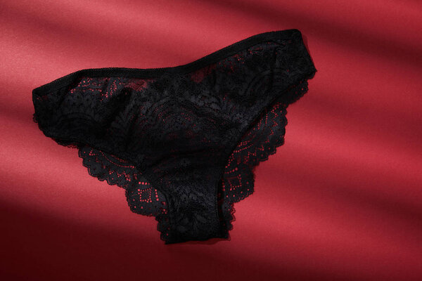 top view of black female panties on red background