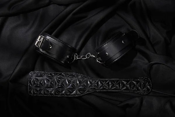 Von Oben Mit Handschellen Und Paddel Auf Schwarzem Textilhintergrund — Stockfoto