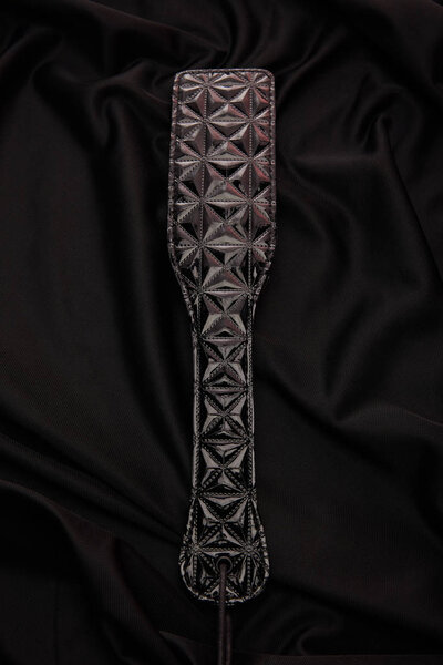 top view of leather paddle on black textile background
