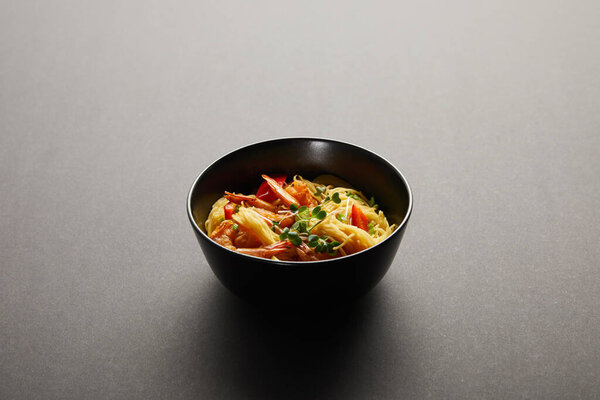 noodles with shrimps and vegetables in bowl on black background