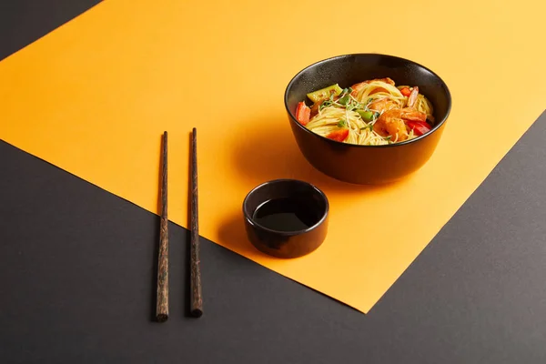 Noodles Shrimps Vegetables Bowl Chopsticks Soy Sauce Black Yellow Background — Stock Photo, Image