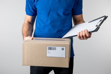 Cropped view of courier holding clipboard and cardboard box isolated on grey clipart
