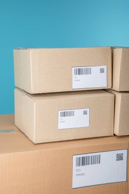 Stacked cardboard packages with barcodes and qr codes isolated on blue clipart