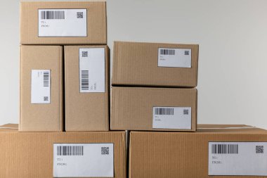 Stacked cardboard boxes with barcodes and qr codes isolated on grey clipart